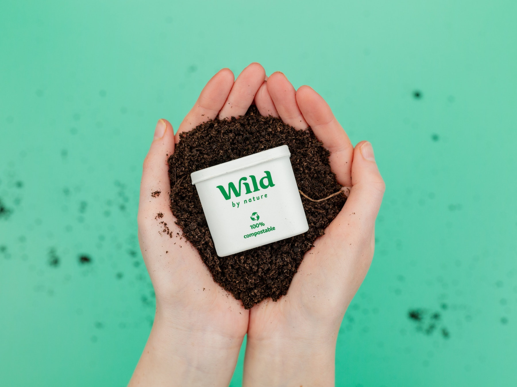 Bildunterschrift: eine Person, die einen Behälter mit Schmutz in den Händen hält