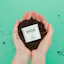 Caption: a person holding a container of dirt in their hands