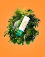 Caption: a tube of sunscreen sitting on top of a lush green plant