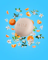 Bildunterschrift: ein Seifenstück mit dem Wort "wild", umgeben von Orangen und Blumen