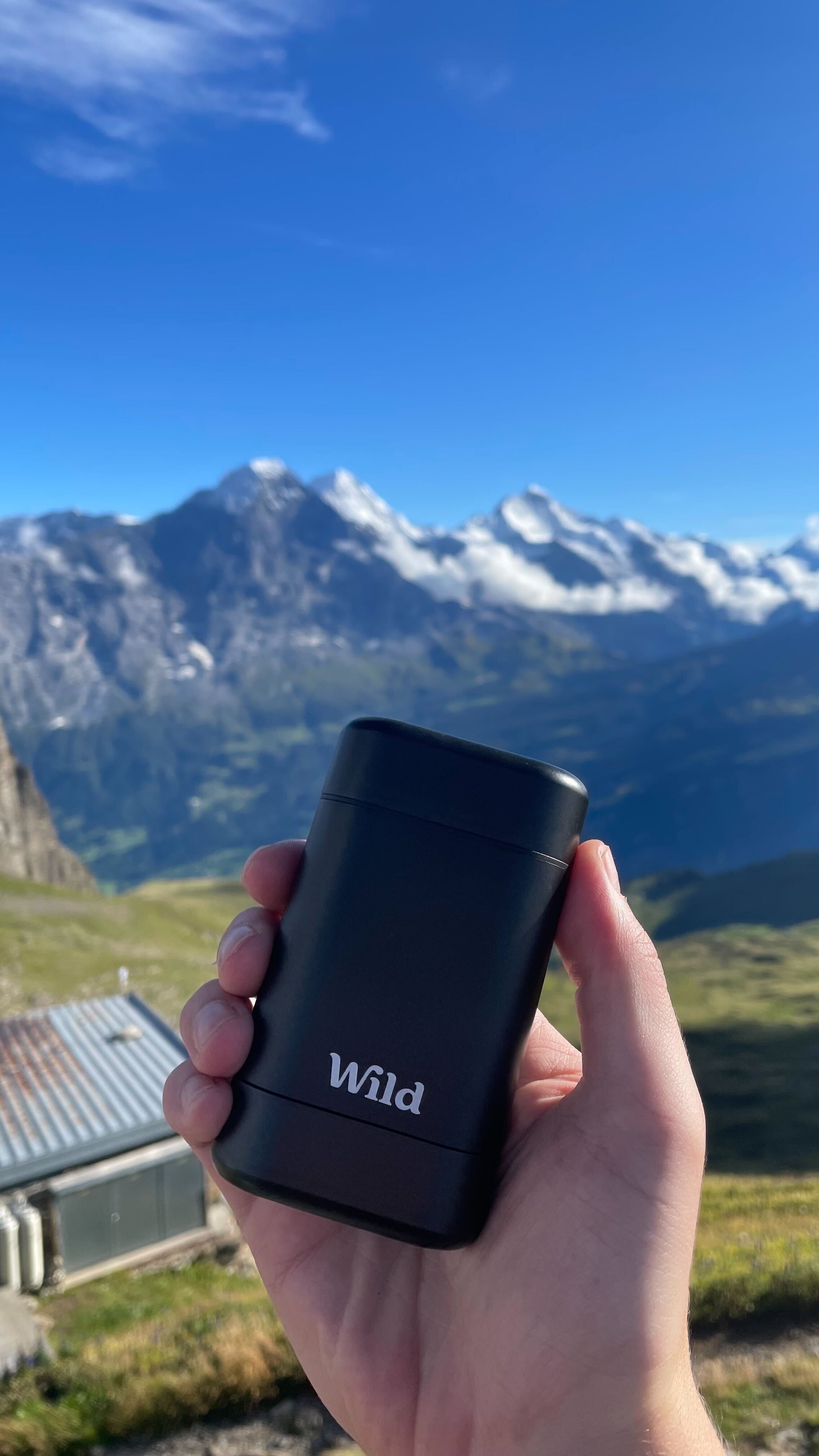 Caption: a hand holding a black lighter in front of a mountain range
