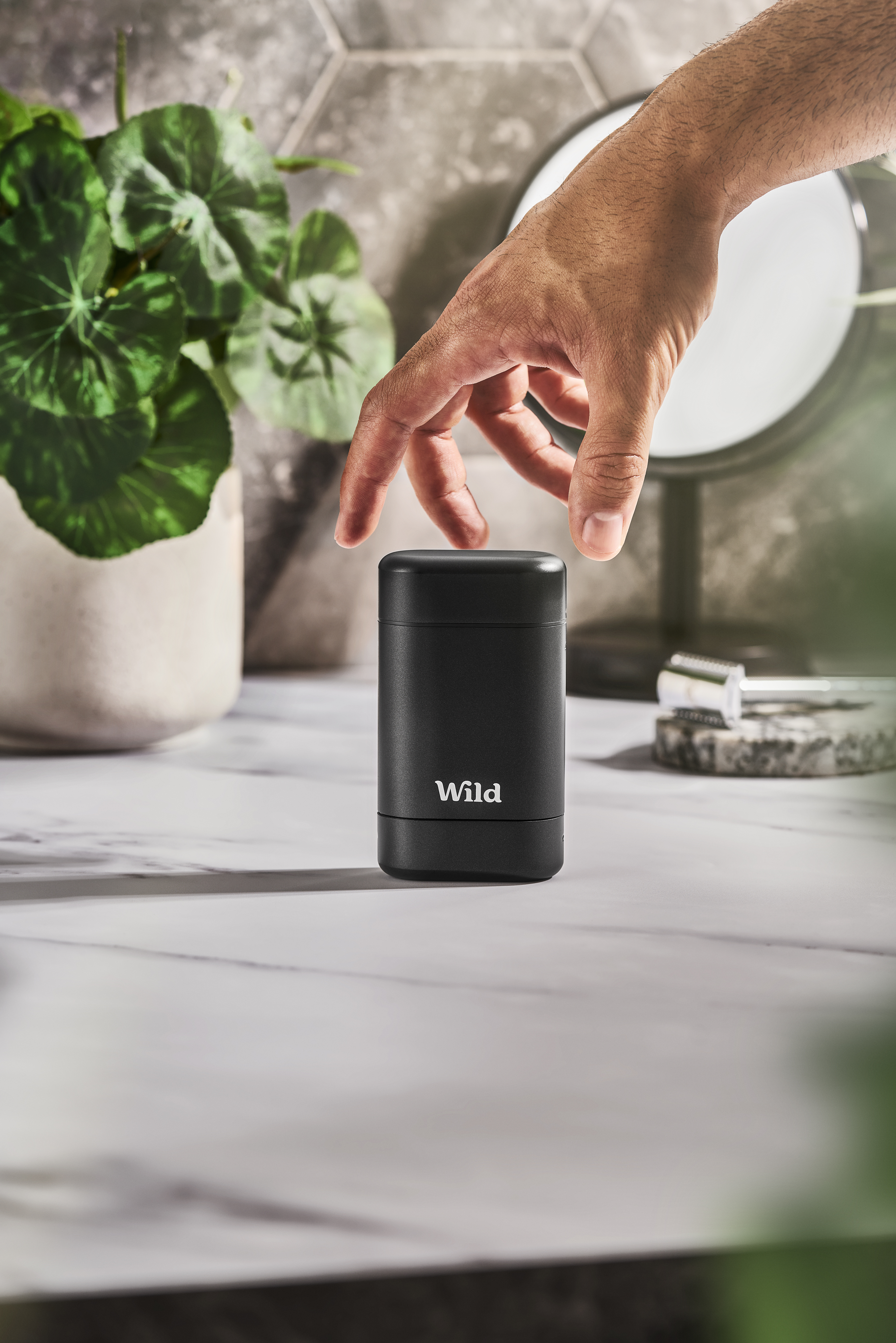 Caption: a hand reaching for a black speaker on a table