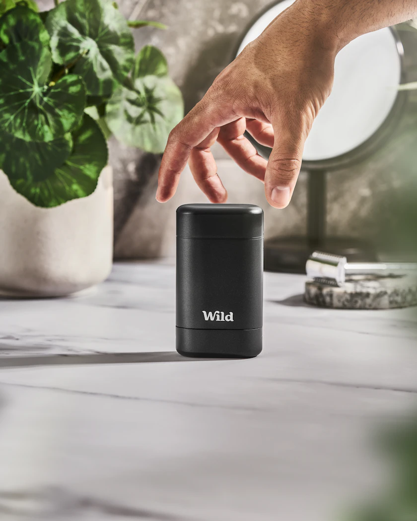 Caption: a hand reaching for a black speaker on a table