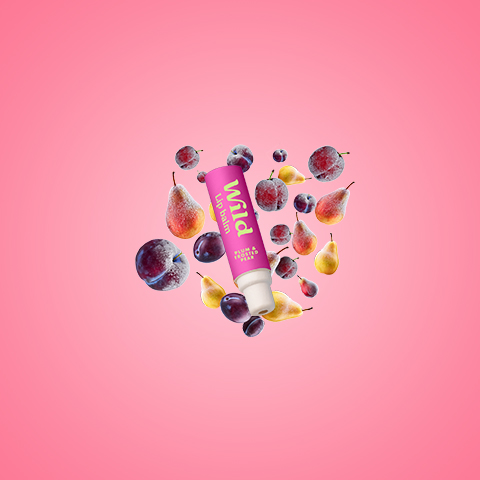 Légende : un tube de beurre à lèvres entouré de fruits sur fond rose