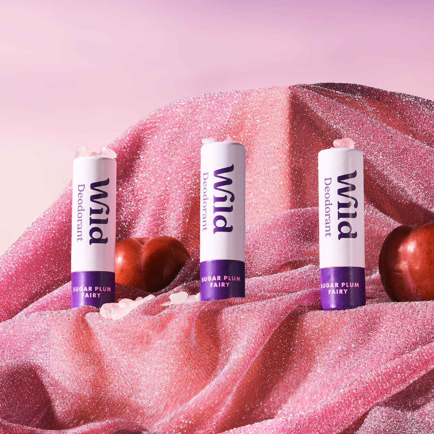 Pie de foto: tres balas de labio sentadas encima de una tela rosa