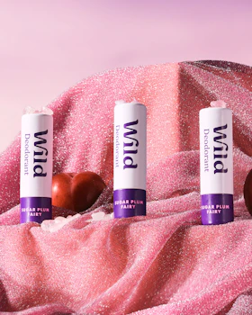 Pie de foto: tres balas de labio sentadas encima de una tela rosa