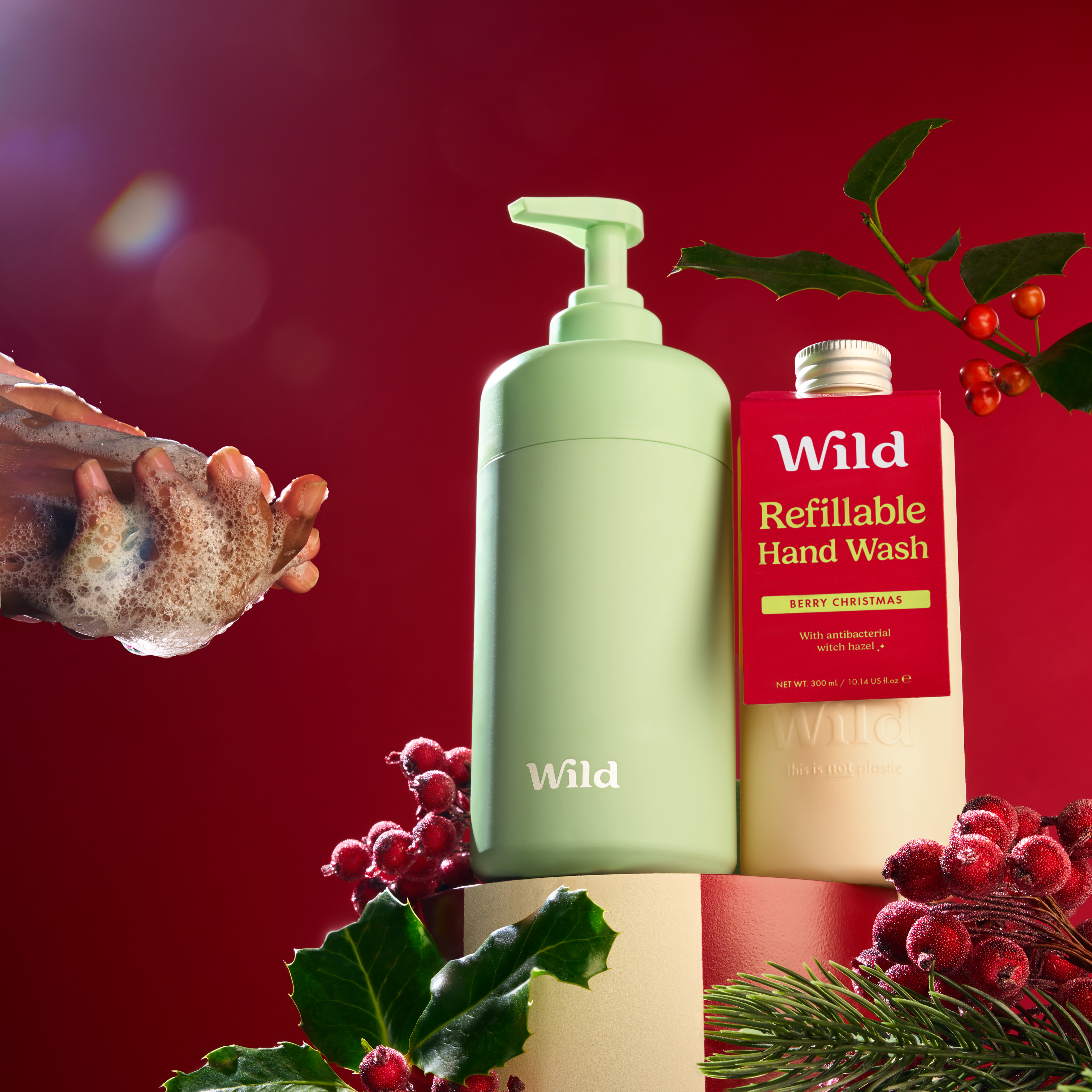 Caption: a hand holding a bottle of hand wash next to a christmas decoration