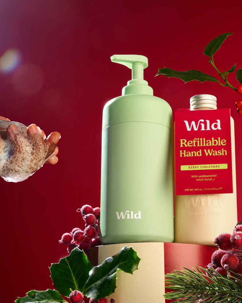 Caption: a hand holding a bottle of hand wash next to a christmas decoration