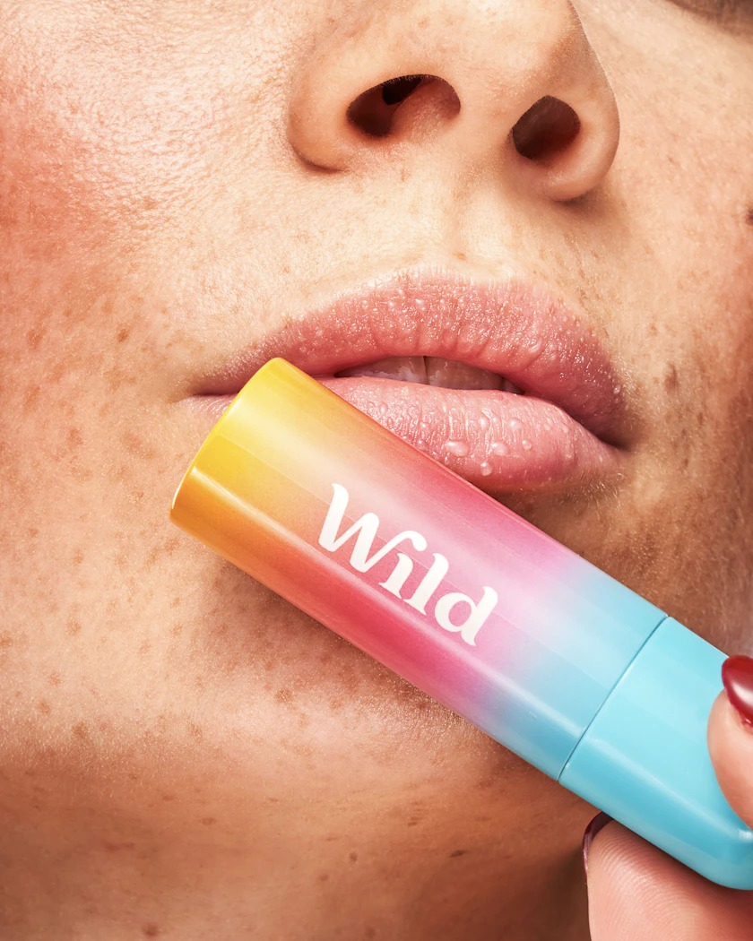 Caption: a woman putting a lip balm on her lip
