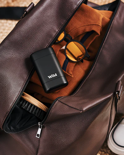 Caption: a brown duffel bag sitting on top of a carpet next to a pair of