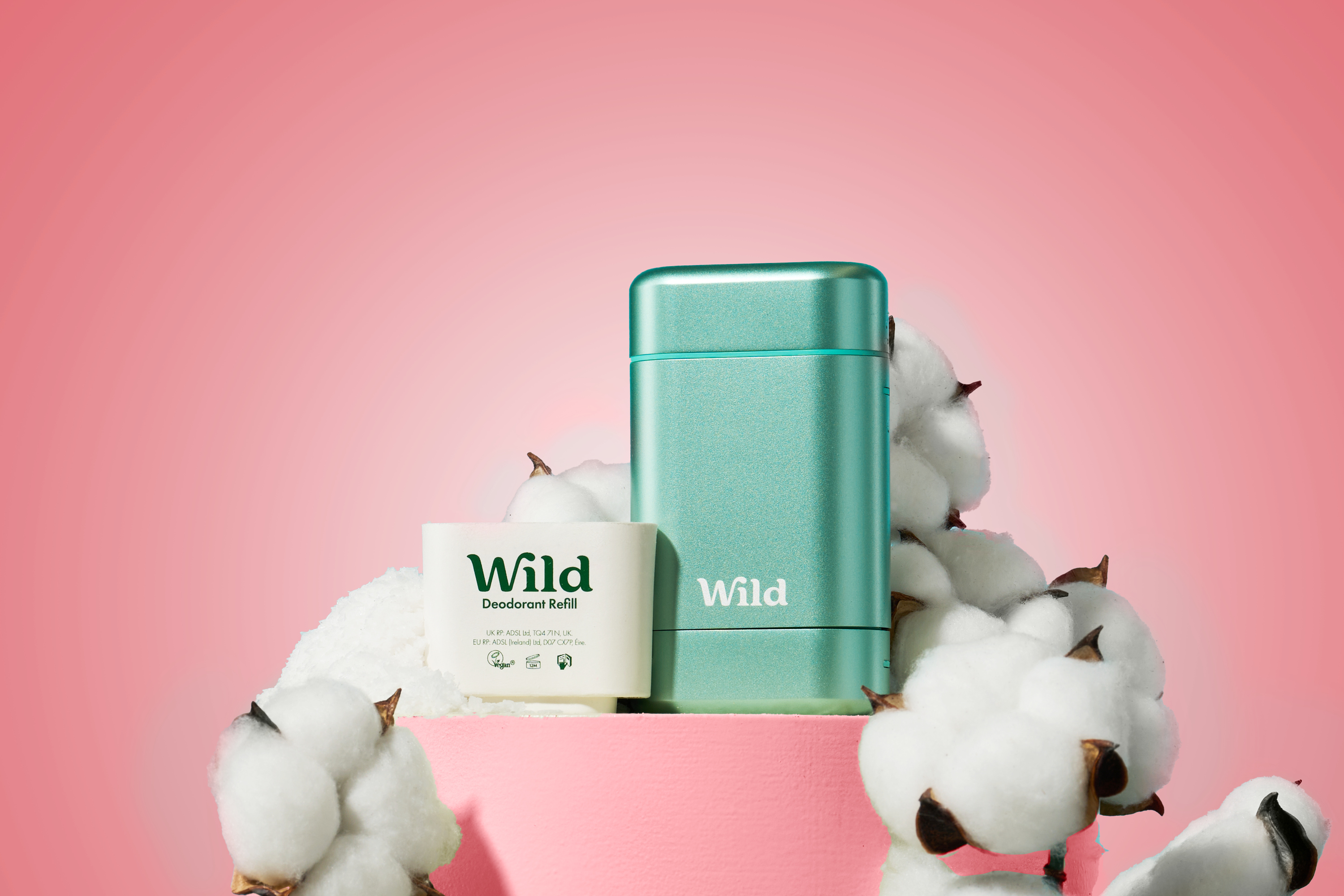 Caption: a pink container with cotton and a bottle of wild