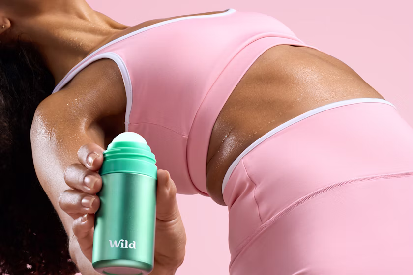 Bijschrift: een vrouw in een roze sportbeha met een groene fles in haar hand