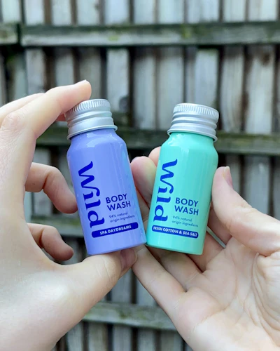 Caption: two hands holding two small bottles of toothpaste