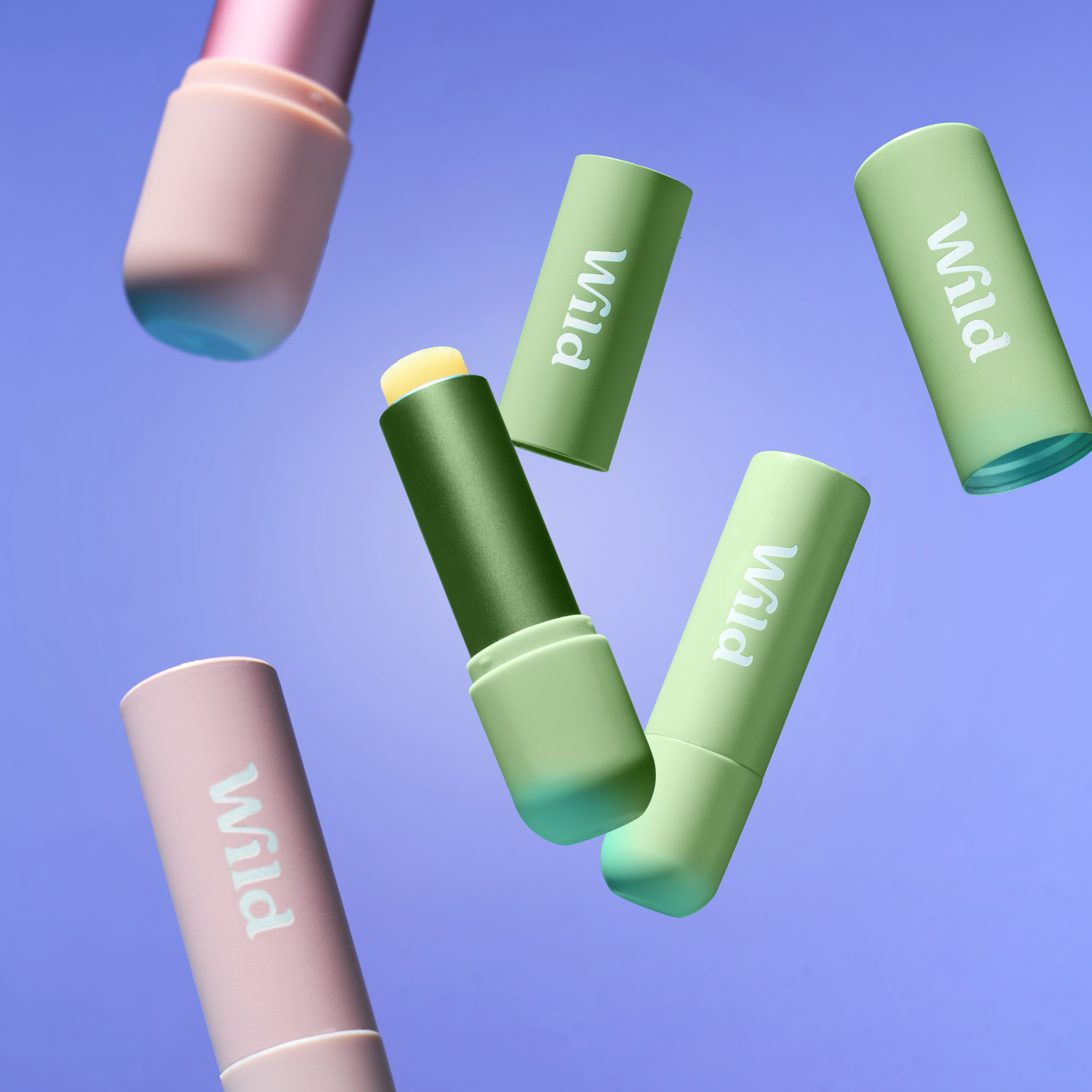 Caption: a group of three green and pink lipsticks flying through the air