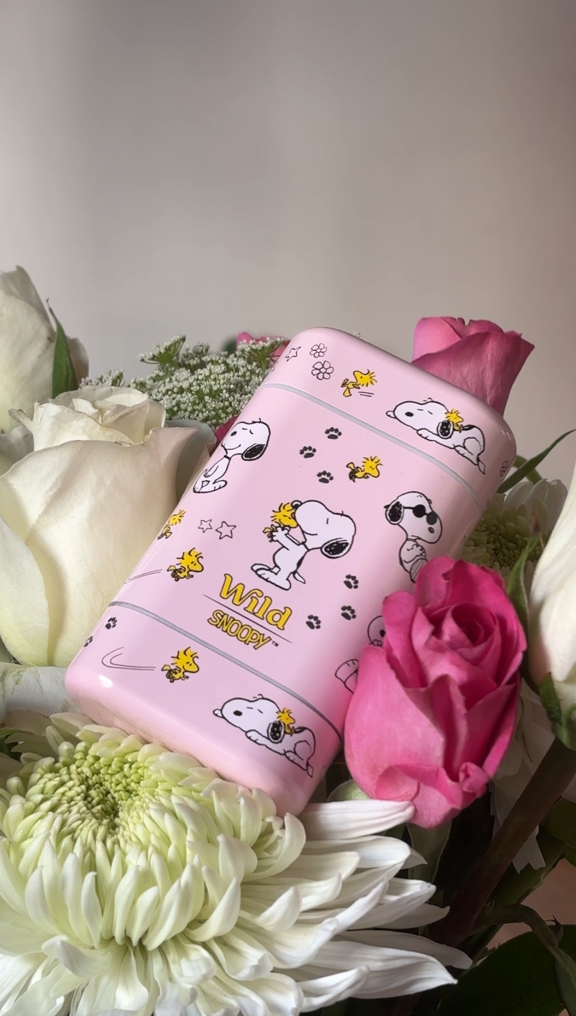 Caption: a pink phone case sitting on top of a bouquet of flowers