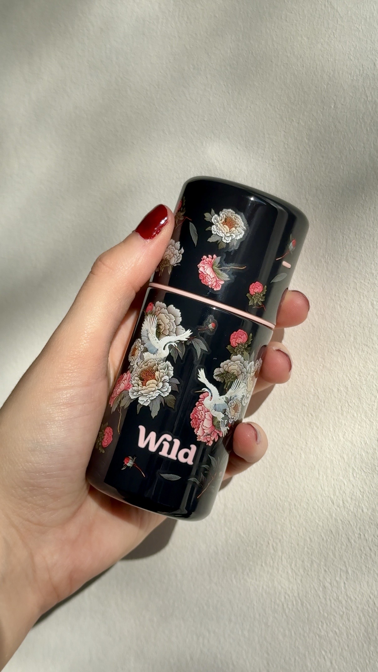 Caption: a woman holding a black coffee mug with flowers on it
