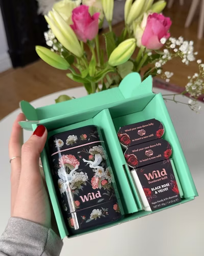 Légende : une personne tenant une boîte de chocolats devant un vase rempli de fleurs