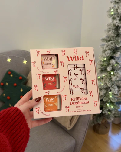 Caption: a person holding a box of food in front of a christmas tree