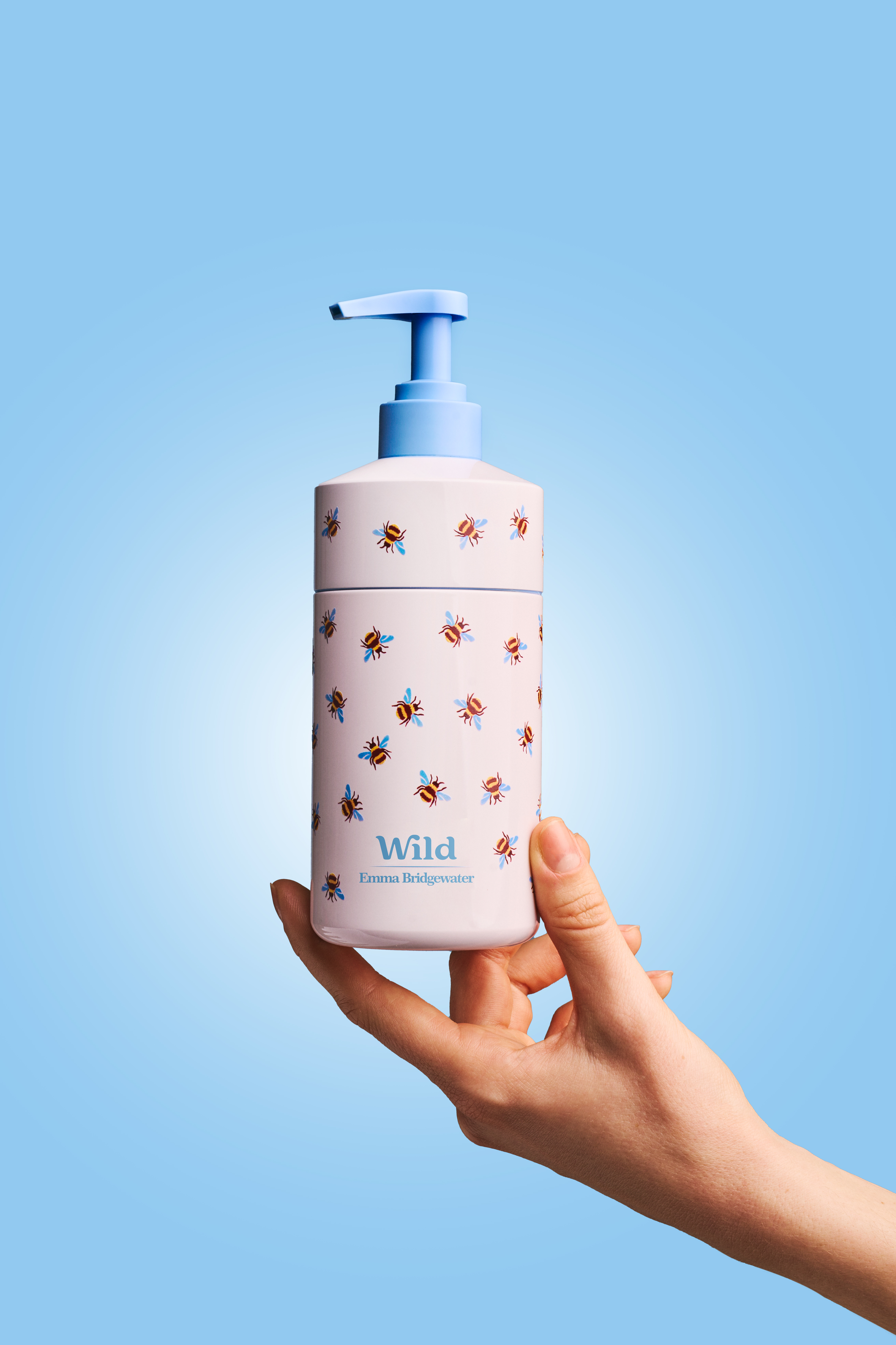 Légende : une main tenant une bouteille blanche et bleue ornée d'abeilles