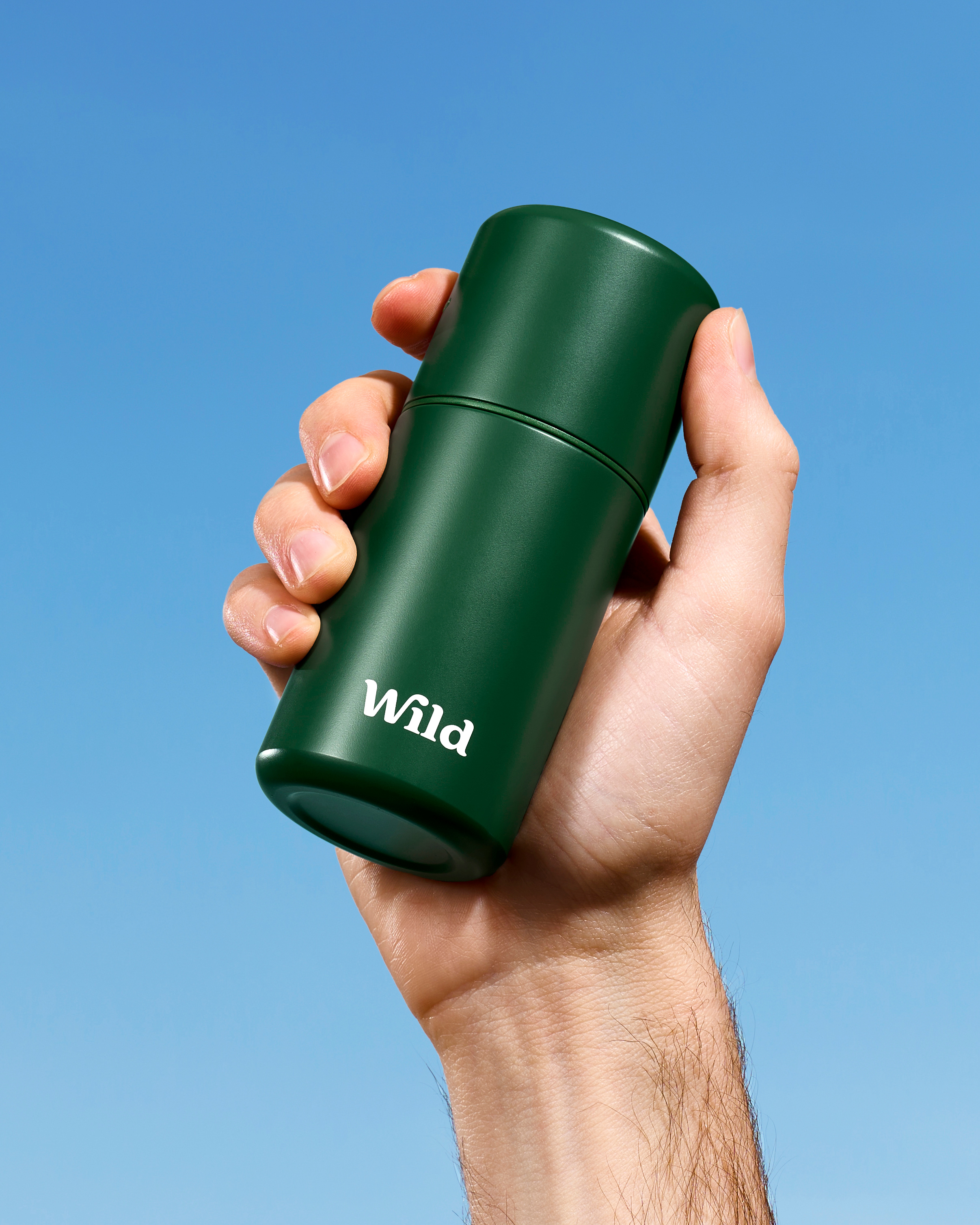 Caption: a hand holding a green travel mug against a blue sky