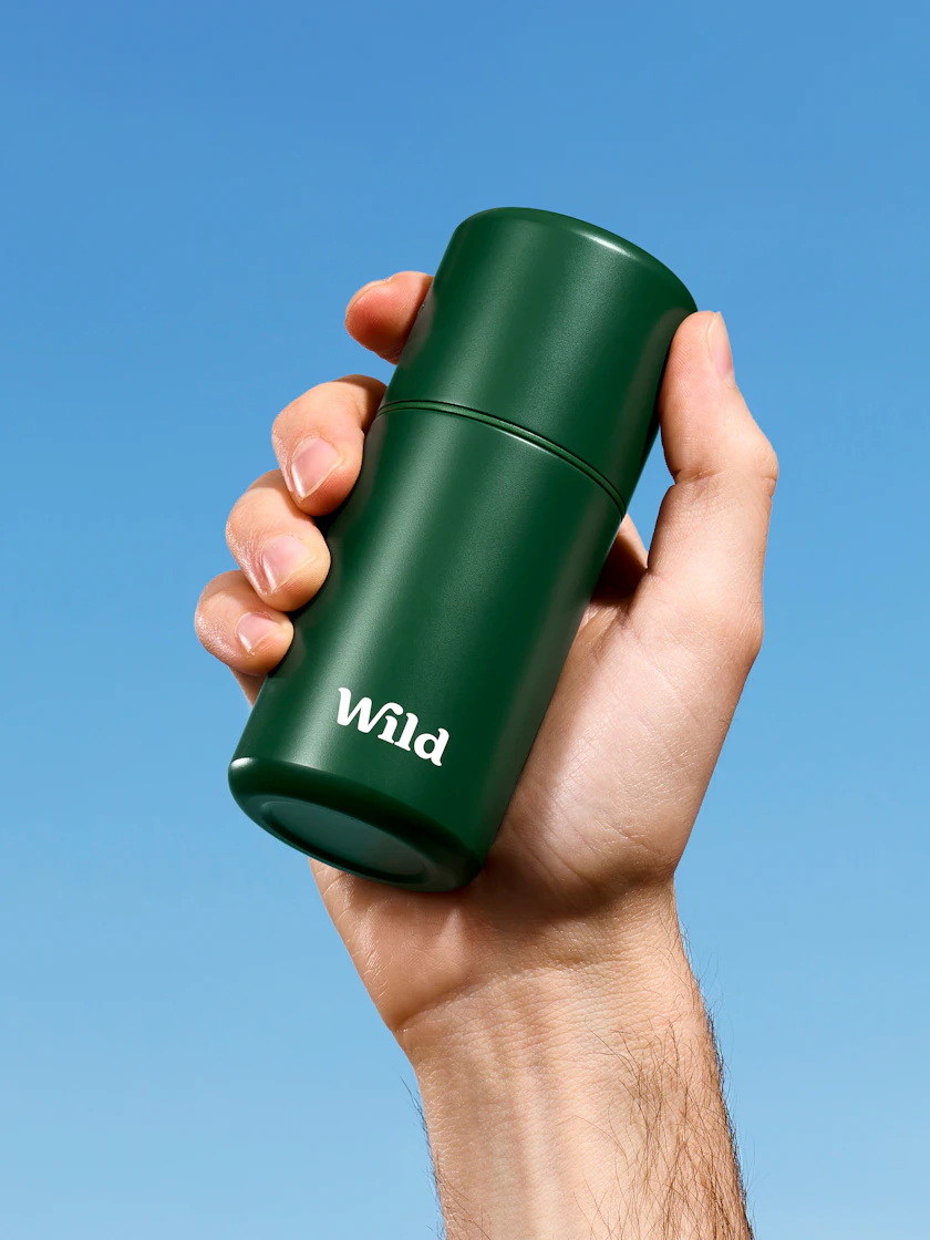 Caption: a hand holding a green travel mug against a blue sky