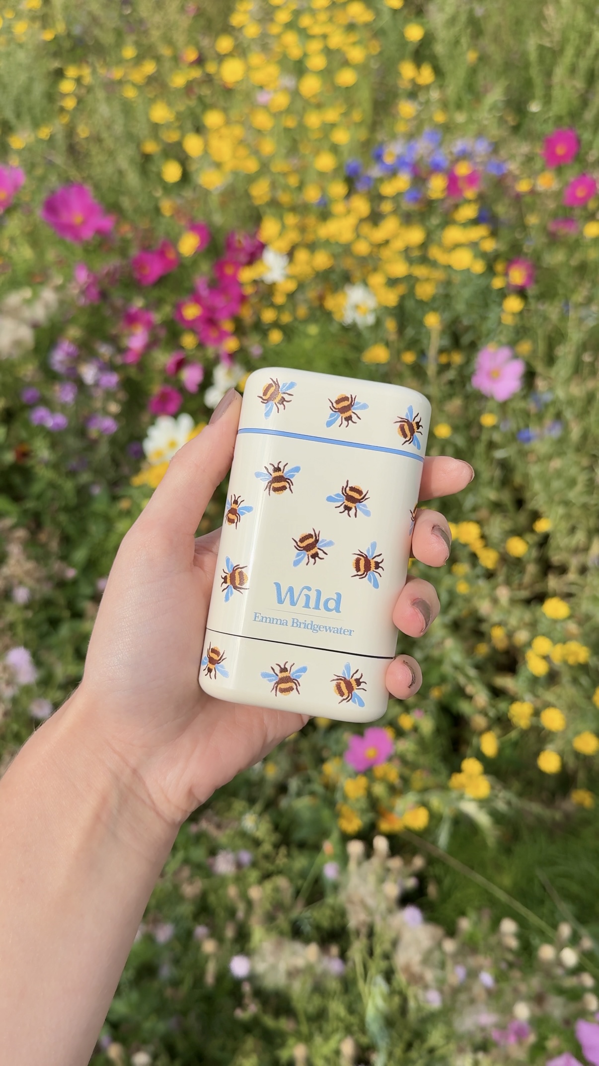 Caption: a person holding a small tin in front of a field of flowers