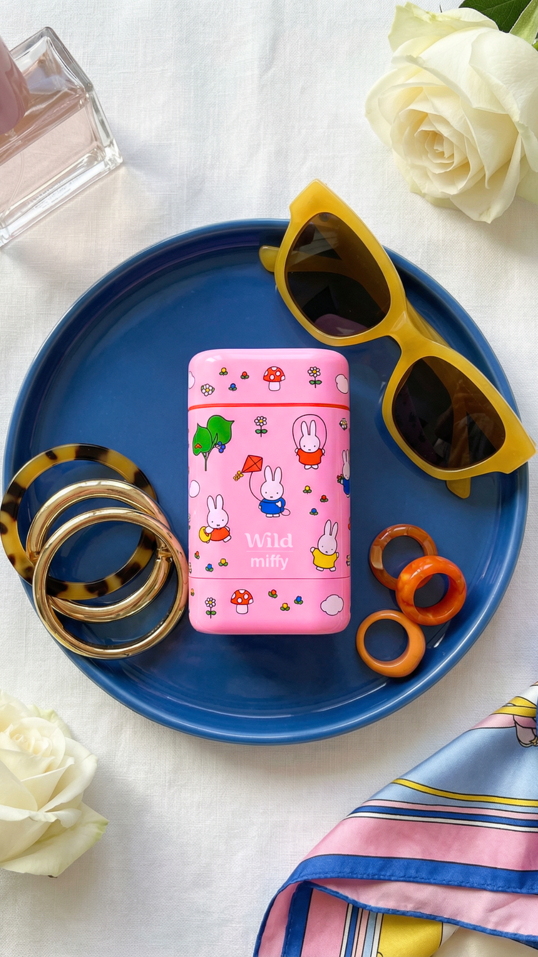 Légende : une assiette bleue sur laquelle sont posées des lunettes de soleil et un cahier rose