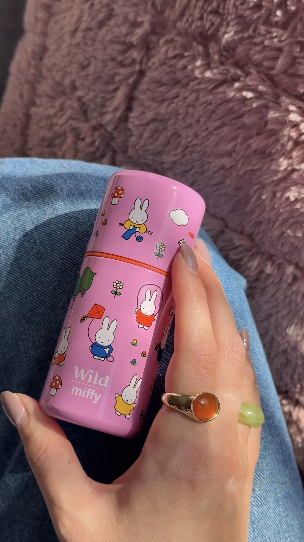 Légende : la main d'une femme tenant un mug de voyage rose