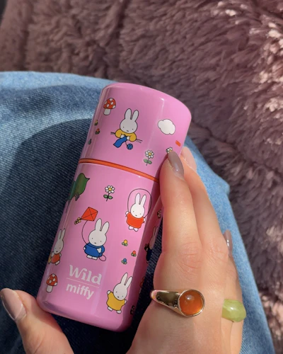 Bildunterschrift: Die Hand einer Frau, die einen rosa Reisebecher hält