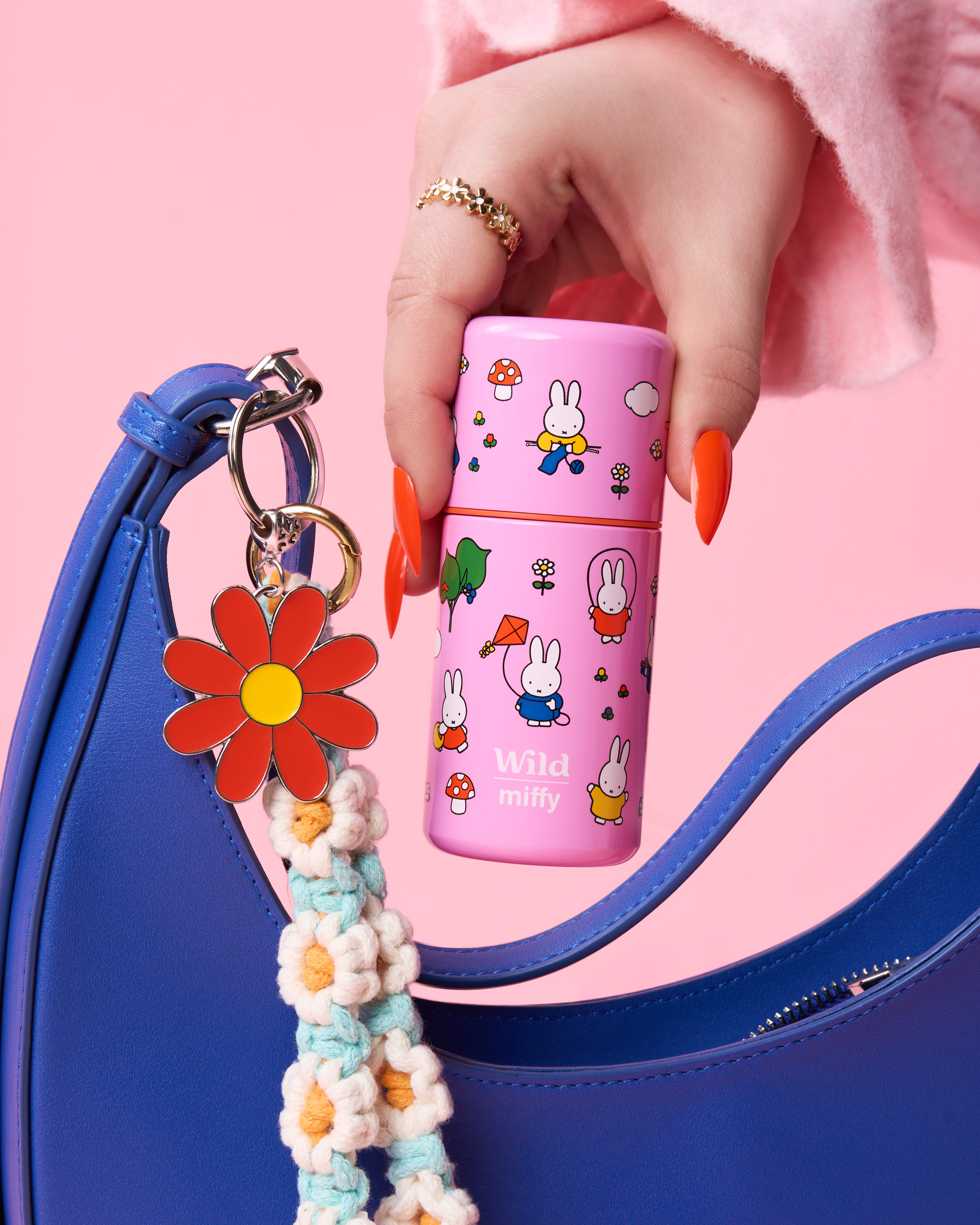 Caption: a woman's hand holding a pink and blue purse and a pink and white