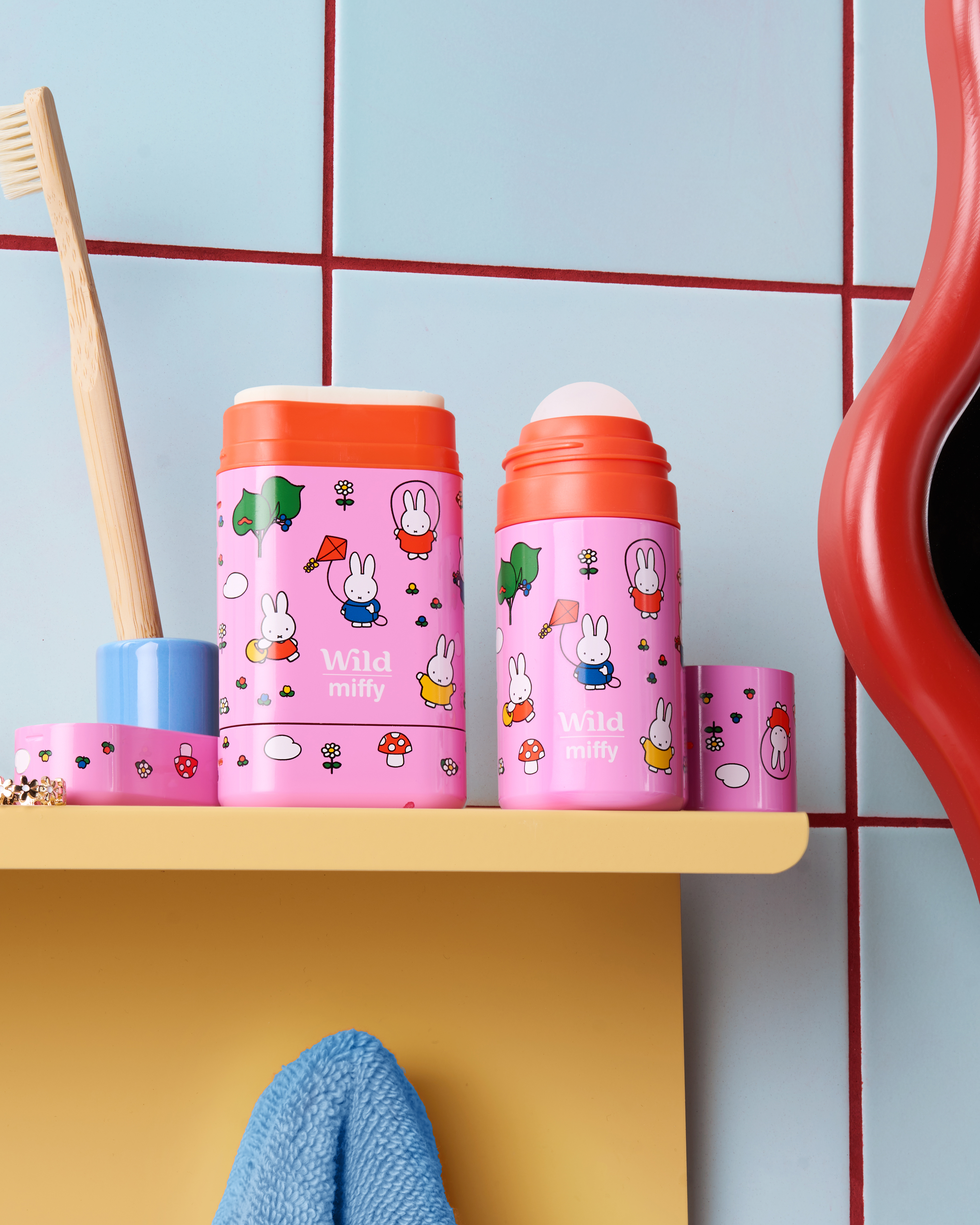 Caption: a shelf with two cups and a toothbrush on it