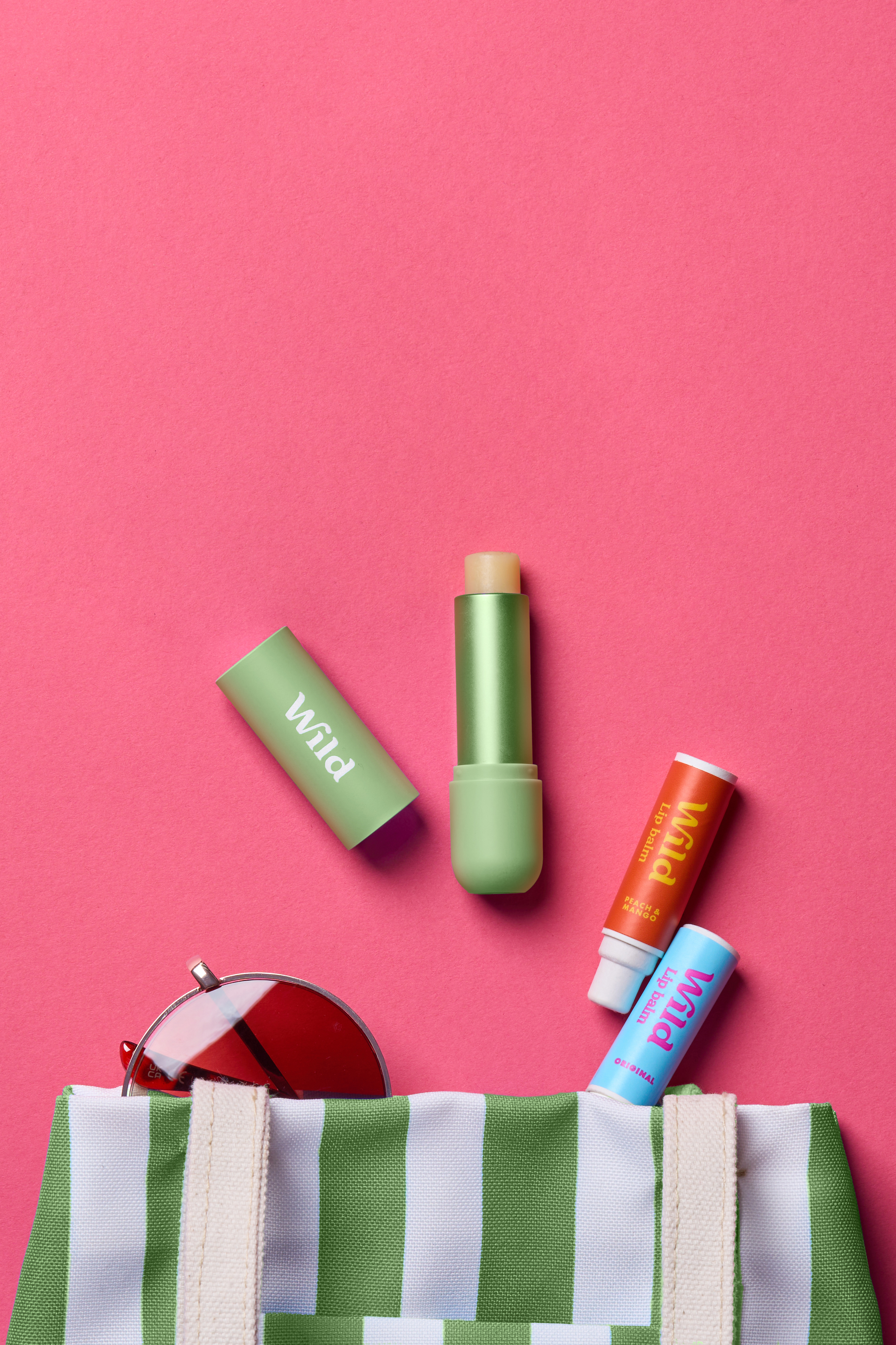 Caption: a green and white striped bag with lipstick, sunglasses, and a lip bale