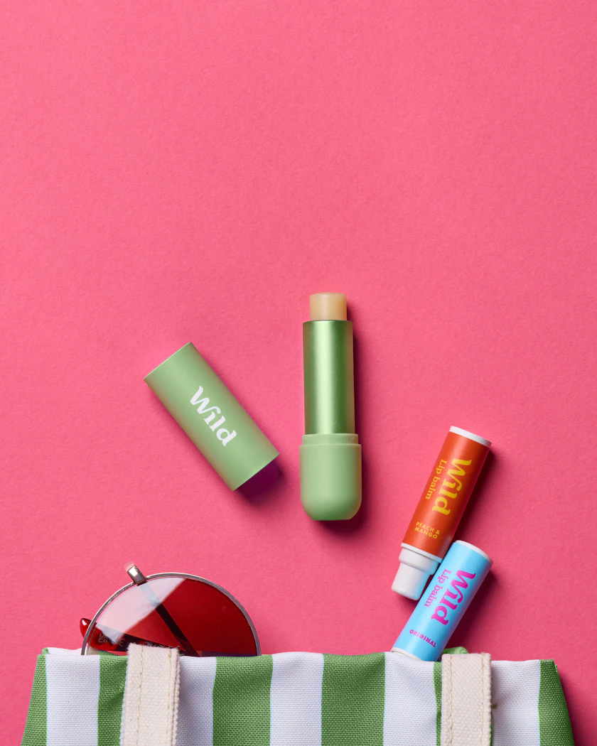Caption: a green and white striped bag with lipstick, sunglasses, and a lip bale