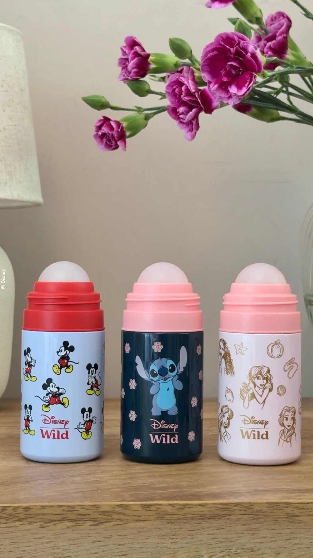 Caption: three baby bottles sitting on a table next to a vase of flowers