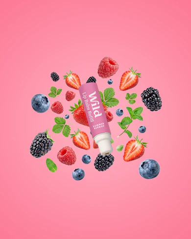 Caption: a tube of lip balm surrounded by berries and strawberries