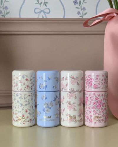 Caption: a pink vase with a pink flower in it and five different colored flowered boxes