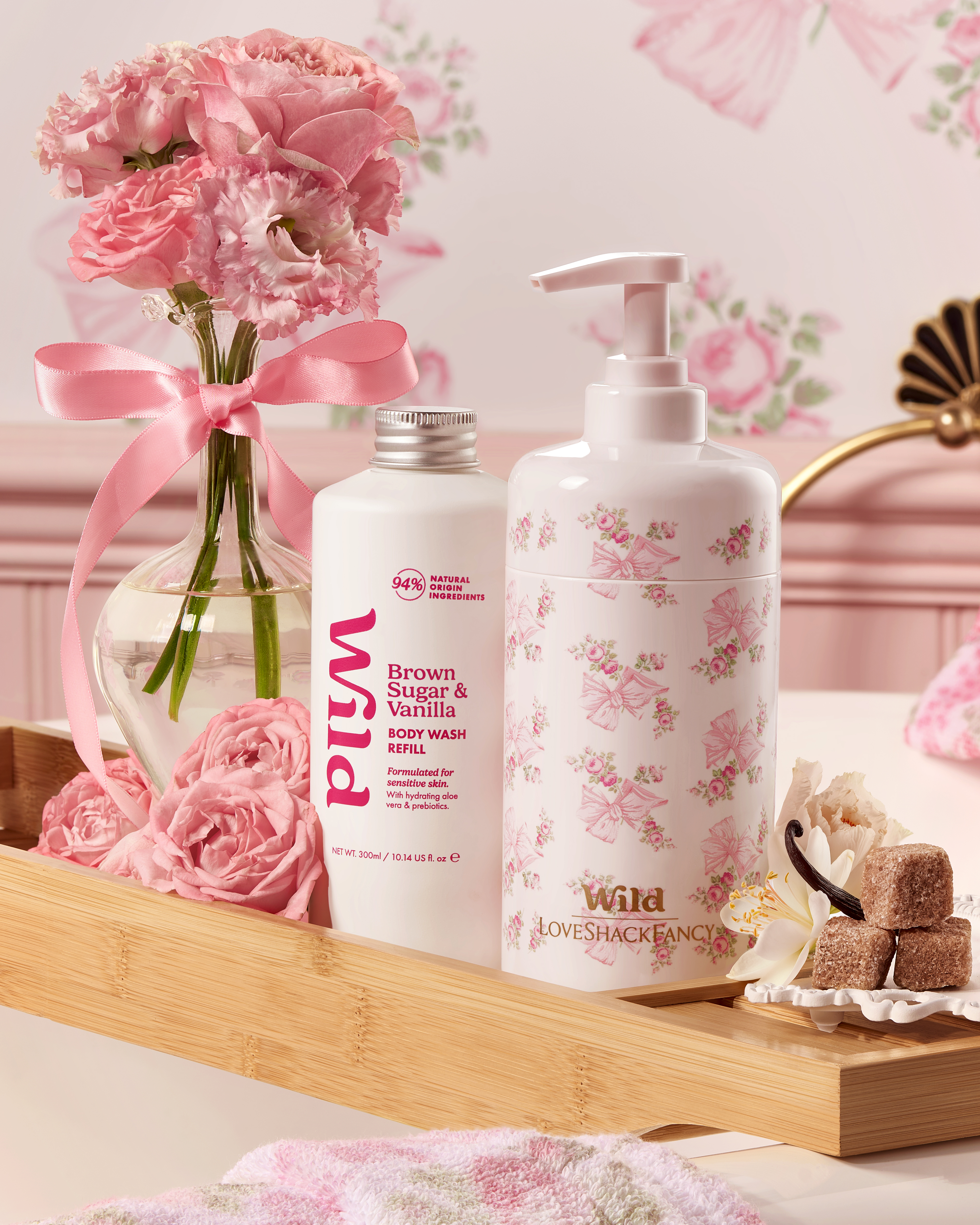 Caption: a bottle of lotion, soap, and a vase of pink flowers on a