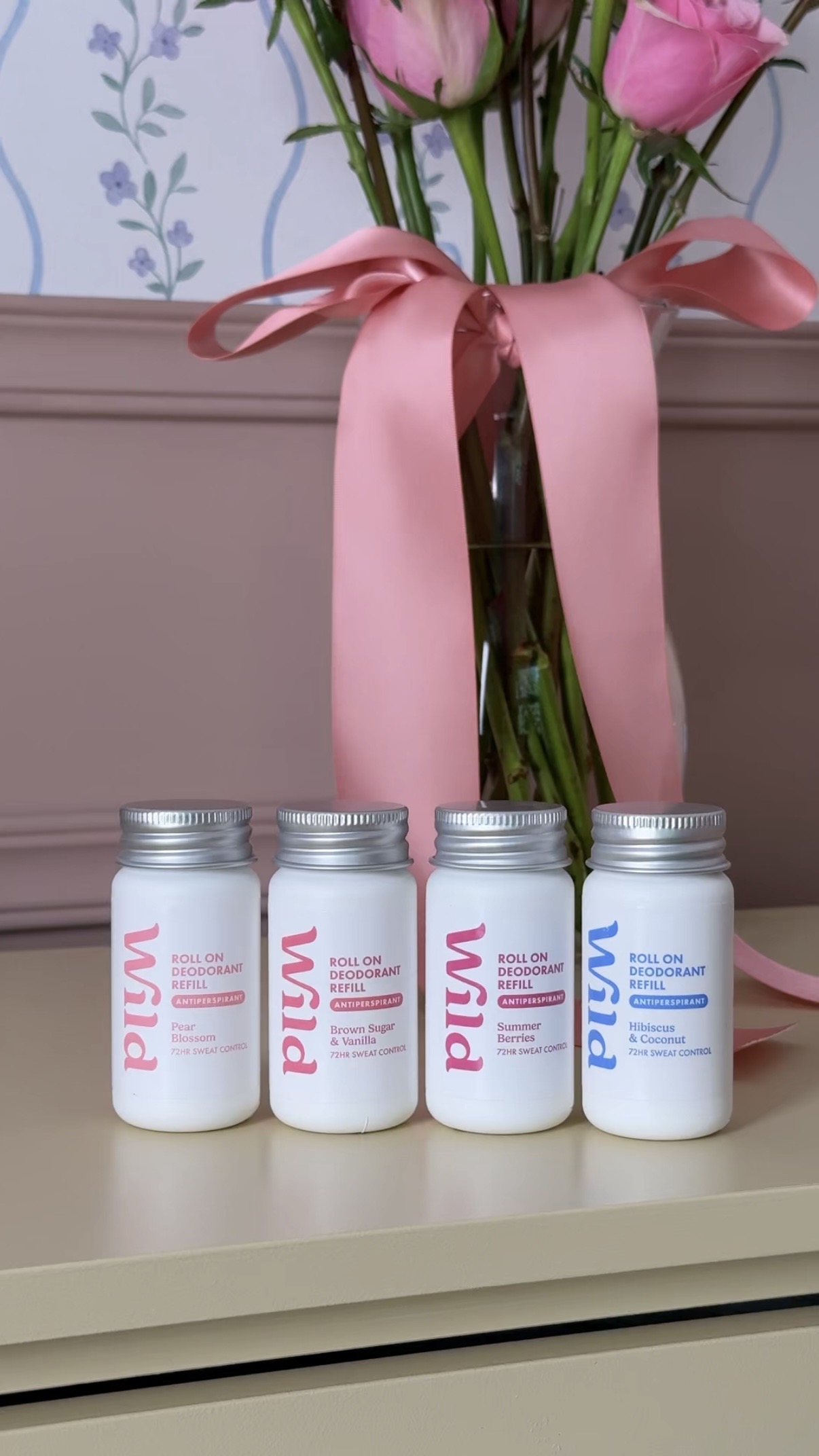 Légende : trois pots de crème posés sur une table, à côté d'un bouquet de fleurs