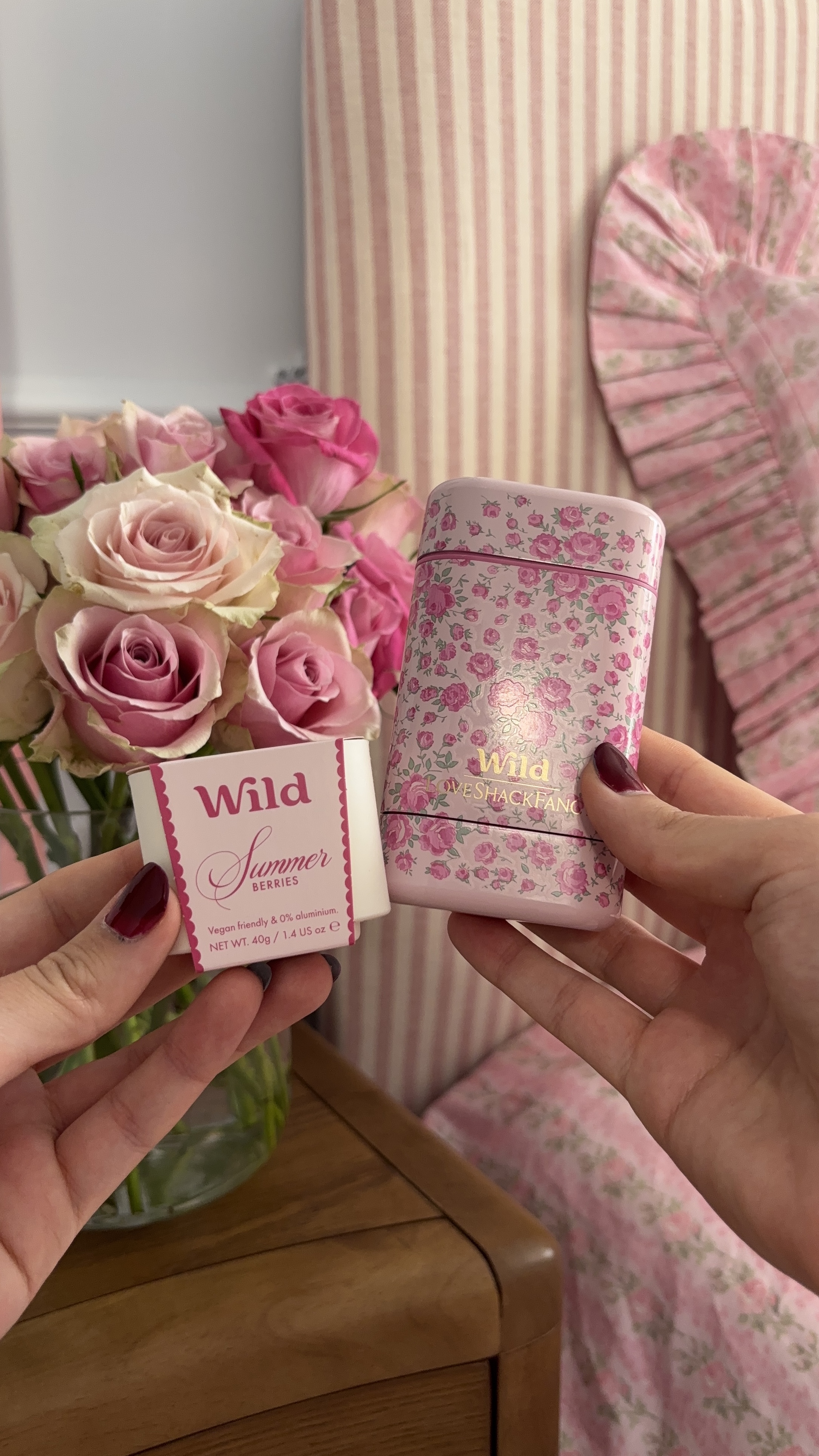 Légende : une femme tenant un coffret de parfum rose et blanc à côté d'un bouquet de roses