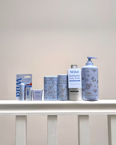 Selection of Wild Cosmetics refillable body wash, lotions, and shampoo bottles on a white shelf.