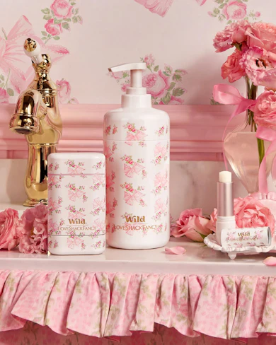Caption: a table topped with a bottle of lotion next to a vase of flowers