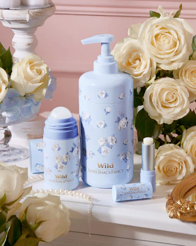 Caption: a table topped with a bottle of lotion next to a vase of flowers