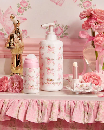 Caption: a table topped with a bottle of lotion next to a vase of flowers