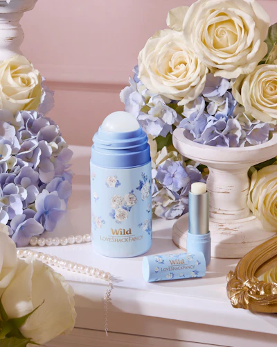 Caption: a vase of flowers and a bottle of perfume