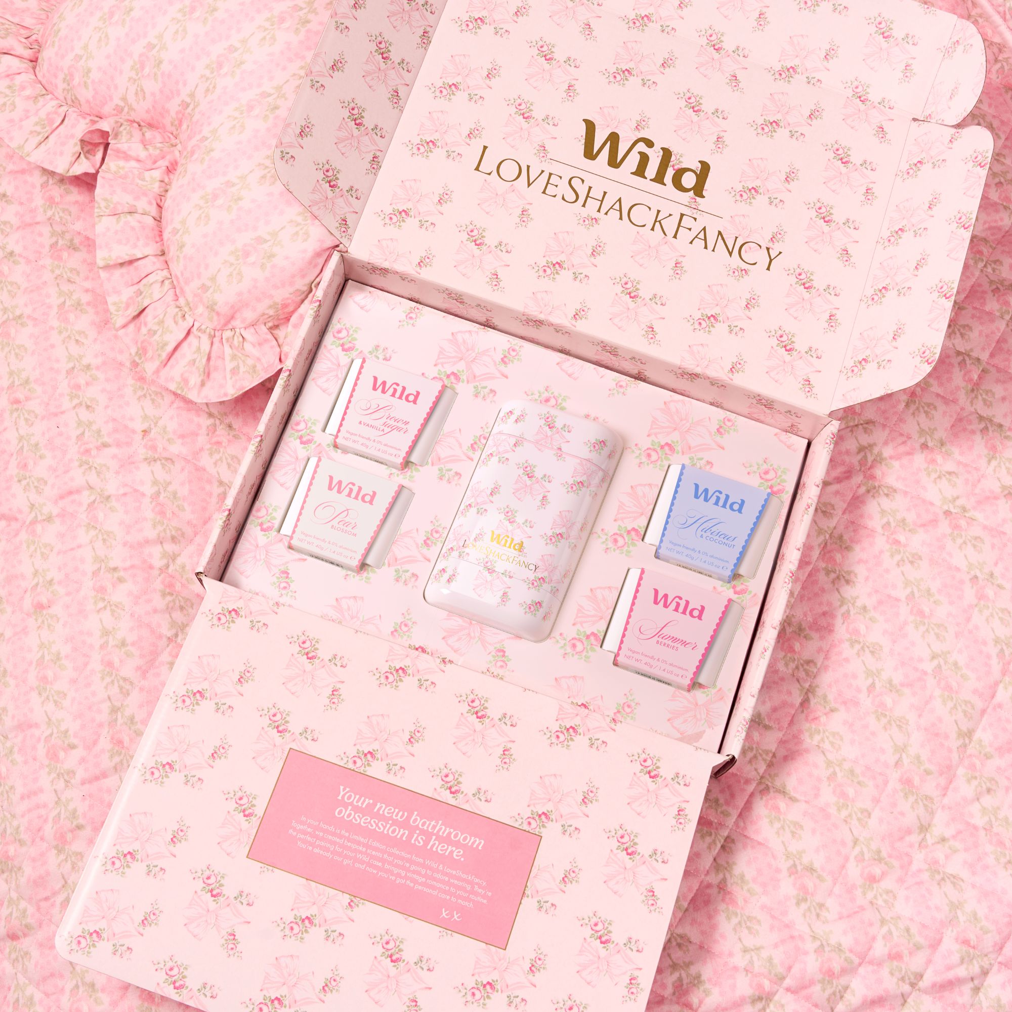 Caption: a pink box with three different perfumes inside of it